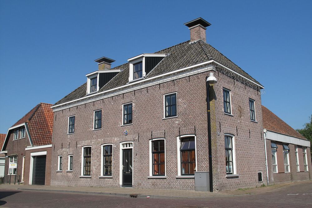 Monumentaal bakstenen hoekpand met dakkapellen in de dorpskern van Heeg