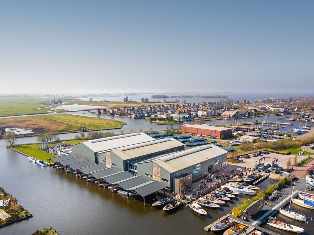 Luchtfoto van de jachthaven van Heeg met steigers vol boten en het Heegermeer op de achtergrond